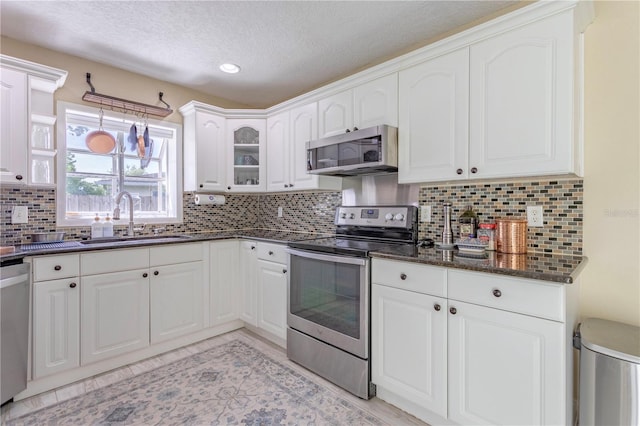 5361 Jade Cir, Belle Isle, FL 32812 - kitchen with appliances with stainless steel finishes, white cabinets, a textured ceiling, glass insert cabinets, and decorative backsplash