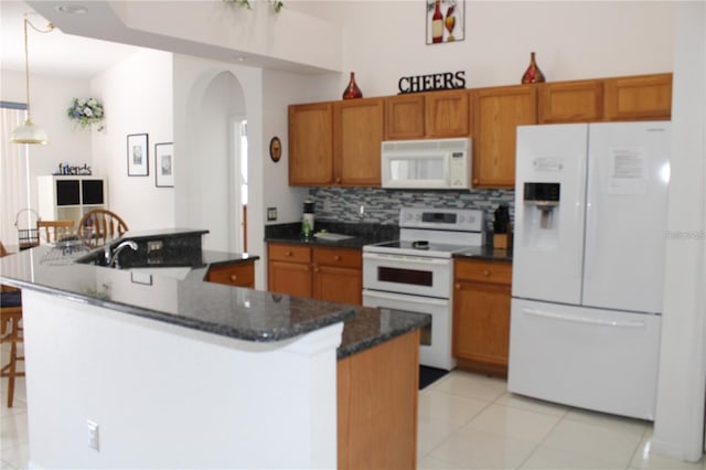 429 Belfry Dr, Davenport, FL 33897 - kitchen with white appliances, arched walkways, brown cabinets, light tile patterned floors, and tasteful backsplash