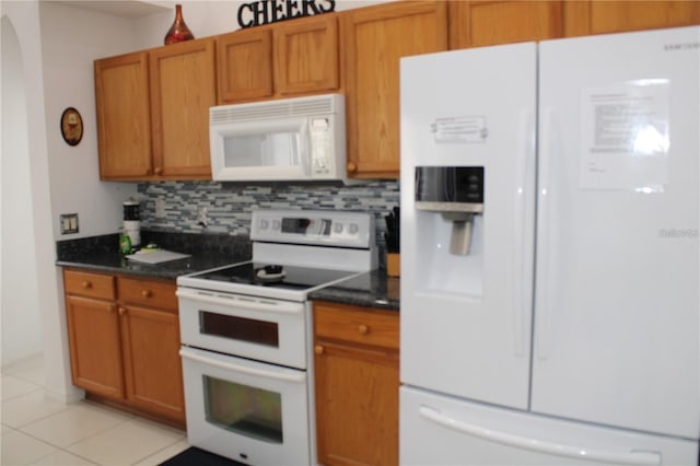 429 Belfry Dr, Davenport, FL 33897 - kitchen with white appliances, tasteful backsplash, dark countertops, and brown cabinets