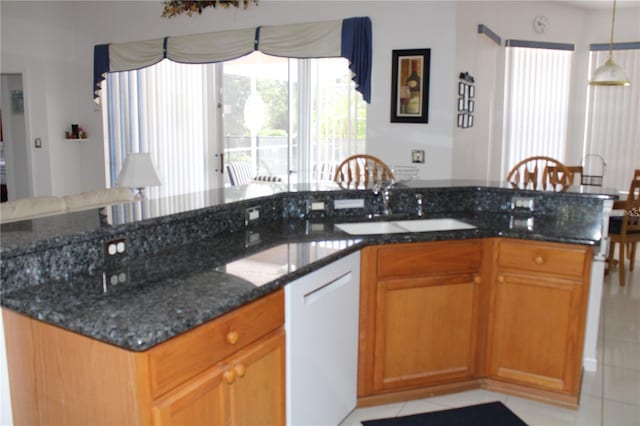 429 Belfry Dr, Davenport, FL 33897 - kitchen featuring light tile patterned flooring, dark stone counters, hanging light fixtures, and brown cabinetry