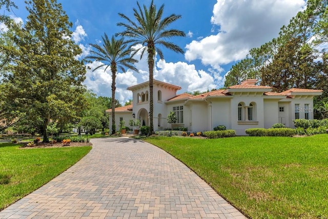 6186 Louise Cove Dr, Windermere, FL 34786 - mediterranean / spanish-style house featuring a chimney, decorative driveway, a tiled roof, stucco siding, and a front yard