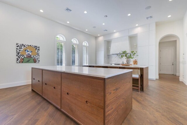6186 Louise Cove Dr, Windermere, FL 34786 - kitchen featuring a large island, arched walkways, dark wood finished floors, and recessed lighting