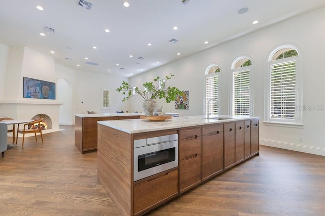 6186 Louise Cove Dr, Windermere, FL 34786 - kitchen featuring a spacious island, wood finished floors, brown cabinets, recessed lighting, and arched walkways
