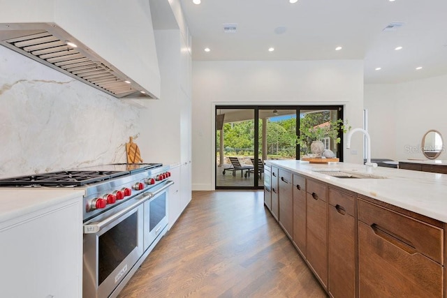 6186 Louise Cove Dr, Windermere, FL 34786 - kitchen featuring range with two ovens, custom exhaust hood, decorative backsplash, light wood-style flooring, and recessed lighting