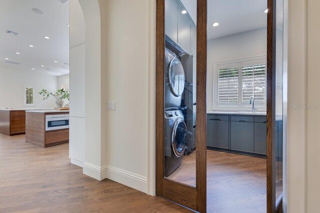 6186 Louise Cove Dr, Windermere, FL 34786 - laundry area featuring stacked washer and clothes dryer, wood finished floors, recessed lighting, and arched walkways