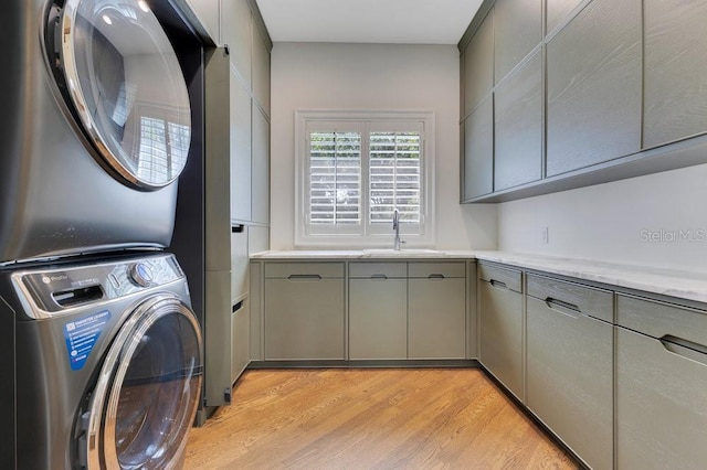 6186 Louise Cove Dr, Windermere, FL 34786 - laundry room with cabinet space, light wood-style flooring, and estacked washer and dryer