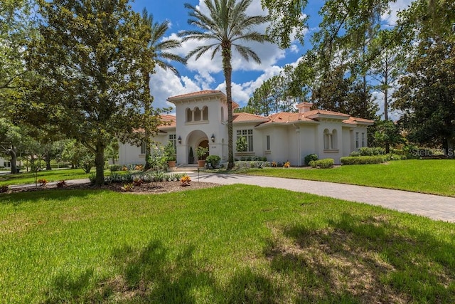 6186 Louise Cove Dr, Windermere, FL 34786 - mediterranean / spanish-style house with stucco siding, a front yard, curved driveway, a tiled roof, and a chimney