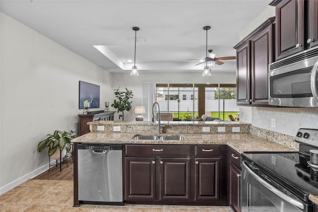 5723 Tarleton Way, Mount Dora, FL 32757 - kitchen featuring appliances with stainless steel finishes, a peninsula, dark brown cabinetry, and light stone countertops