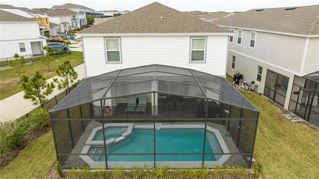 1907 Summer Dr, Davenport, FL 33897 - back of property with a shingled roof, a pool with connected hot tub, glass enclosure, and a patio area