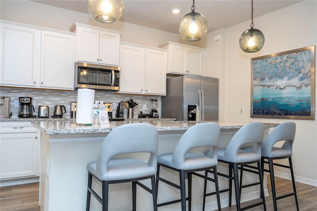 1907 Summer Dr, Davenport, FL 33897 - kitchen featuring stainless steel appliances, backsplash, white cabinets, a kitchen bar, and pendant lighting