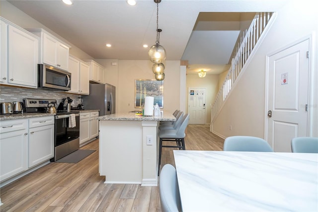 1907 Summer Dr, Davenport, FL 33897 - kitchen with stainless steel appliances, a breakfast bar area, recessed lighting, light wood-style floors, and decorative backsplash