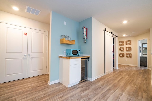 1907 Summer Dr, Davenport, FL 33897 - kitchen featuring wine cooler, a barn door, light wood-style floors, white cabinets, and recessed lighting