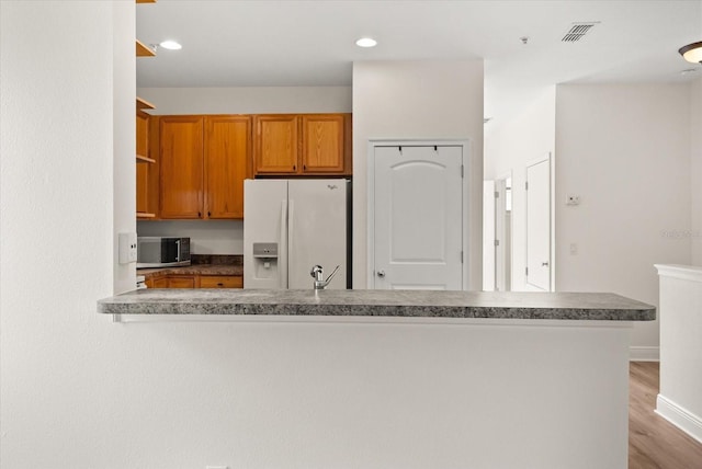 11 W Harding St Unit E, Orlando, FL 32806 - kitchen featuring white fridge with ice dispenser, stainless steel microwave, brown cabinets, wood finished floors, and open shelves