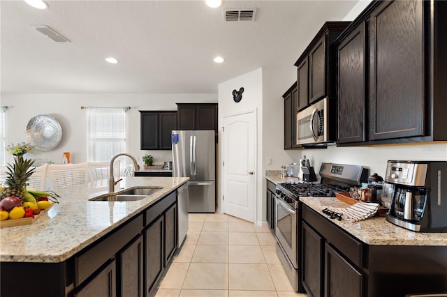 8020 Oak Shadow Ct, Davenport, FL 33837 - kitchen with appliances with stainless steel finishes, light stone countertops, light tile patterned floors, a kitchen island with sink, and recessed lighting