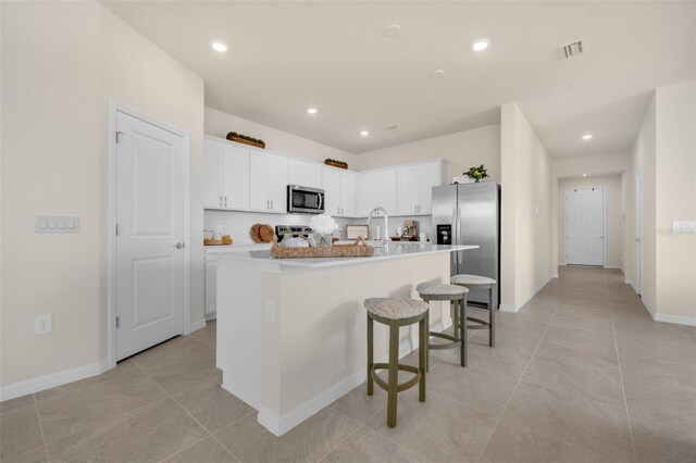 3702 Haddon Ave, Davenport, FL 33837 - kitchen featuring stainless steel appliances, a center island with sink, white cabinetry, a kitchen breakfast bar, and recessed lighting