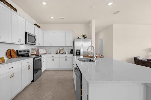 3702 Haddon Ave, Davenport, FL 33837 - kitchen with stainless steel appliances, a kitchen island with sink, recessed lighting, white cabinetry, and tasteful backsplash