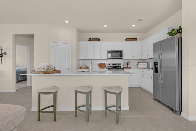 3702 Haddon Ave, Davenport, FL 33837 - kitchen featuring appliances with stainless steel finishes, a kitchen breakfast bar, white cabinetry, decorative backsplash, and recessed lighting