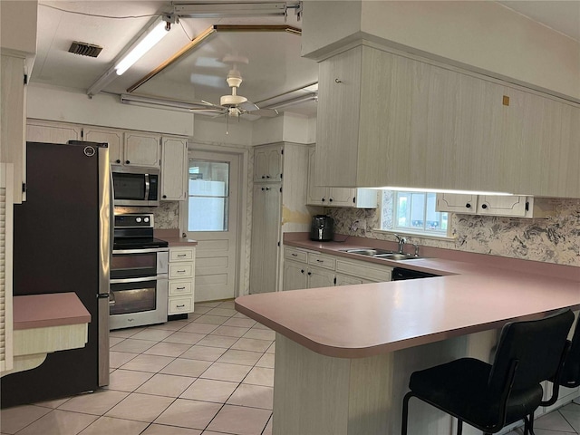 608 Knowles Rd, Brandon, FL 33511 - kitchen featuring appliances with stainless steel finishes, a peninsula, light tile patterned floors, a ceiling fan, and tasteful backsplash