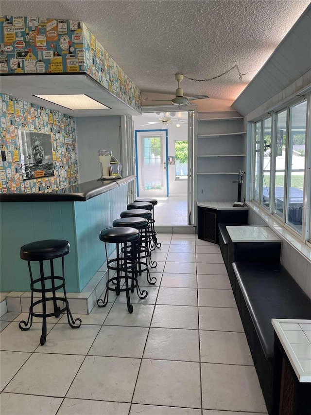 608 Knowles Rd, Brandon, FL 33511 - kitchen with a ceiling fan, a textured ceiling, plenty of natural light, light tile patterned floors, and a breakfast bar