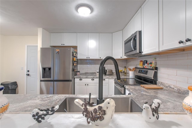 663 Courtland Blvd, Deltona, FL 32738 - kitchen with stainless steel appliances, white cabinets, backsplash, and light stone counters