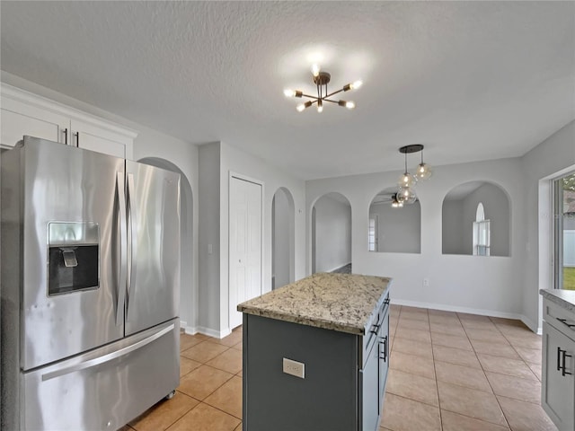 1301 Brenway Dr, Mascotte, FL 34753 - kitchen with stainless steel refrigerator with ice dispenser, light tile patterned floors, a chandelier, white cabinetry, and a textured ceiling