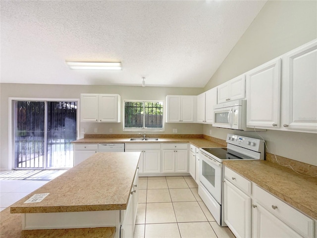 6460 Preakness Dr, Orlando, FL 32818 - kitchen featuring white appliances, light tile patterned floors, white cabinetry, a textured ceiling, and vaulted ceiling