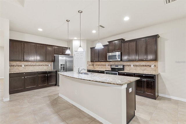 2236 Landside Dr, Valrico, FL 33594 - kitchen featuring appliances with stainless steel finishes, dark brown cabinets, tasteful backsplash, an island with sink, and light stone countertops