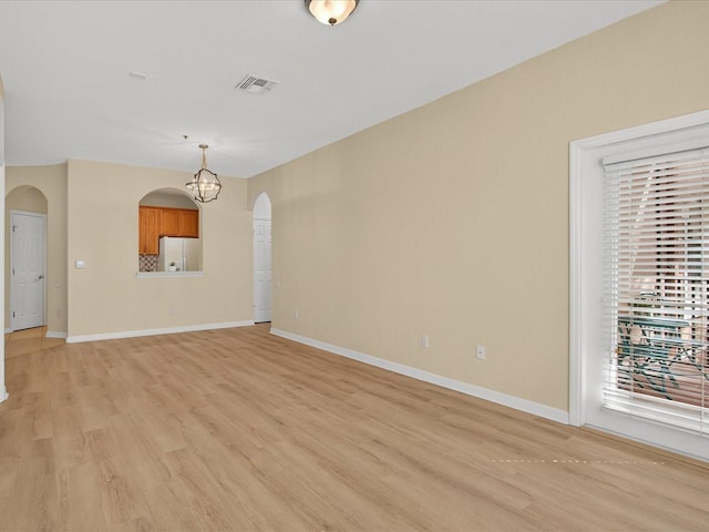 1353 Venezia Ct Unit 205, Davenport, FL 33896 - unfurnished living room featuring arched walkways, light wood-style floors, a chandelier, and healthy amount of natural light
