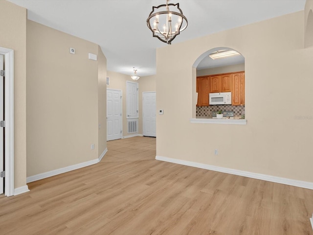 1353 Venezia Ct Unit 205, Davenport, FL 33896 - spare room featuring a chandelier, light wood-style flooring, and arched walkways