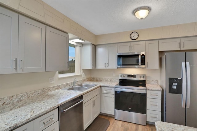 749 Ridge Blvd, South Daytona, FL 32119 - kitchen featuring stainless steel appliances, light wood finished floors, a textured ceiling, and light stone countertops