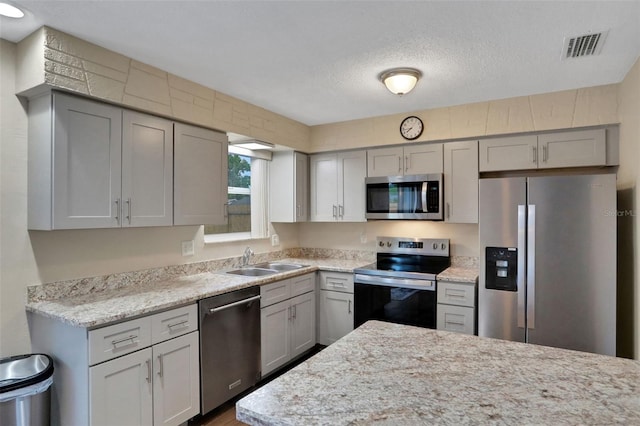 749 Ridge Blvd, South Daytona, FL 32119 - kitchen with appliances with stainless steel finishes, gray cabinetry, a textured ceiling, wood finished floors, and light stone counters