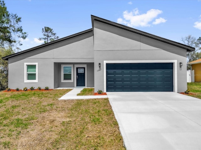 13673 SW 43th Cir, Ocala, FL 34473 - view of front of property featuring an attached garage, stucco siding, concrete driveway, and a front lawn