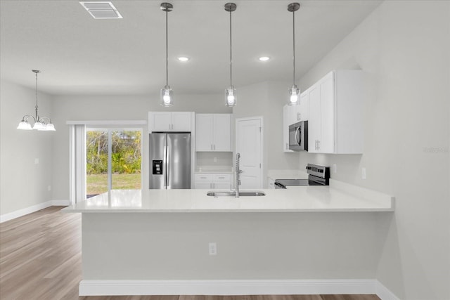 13673 SW 43th Cir, Ocala, FL 34473 - kitchen with appliances with stainless steel finishes, light countertops, a peninsula, white cabinets, and light wood-type flooring