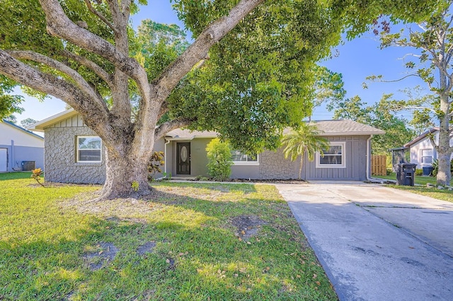1175 Tracy Dr, Port Orange, FL 32129 - view of front of home with board and batten siding, a front yard, stone siding, and driveway