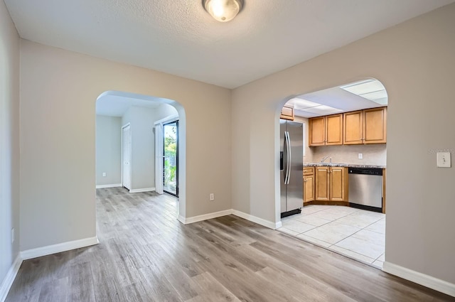 1175 Tracy Dr, Port Orange, FL 32129 - kitchen with appliances with stainless steel finishes, arched walkways, light wood-style flooring, and a textured ceiling