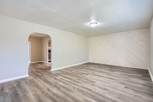 1175 Tracy Dr, Port Orange, FL 32129 - spare room featuring arched walkways, a textured ceiling, and wood finished floors