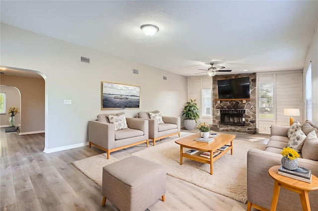 1175 Tracy Dr, Port Orange, FL 32129 - living room featuring arched walkways, ceiling fan, a stone fireplace, and wood finished floors