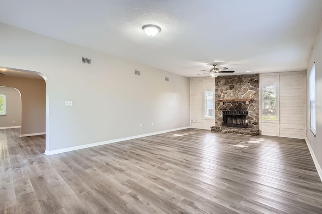 1175 Tracy Dr, Port Orange, FL 32129 - unfurnished living room with ceiling fan, a fireplace, arched walkways, and wood finished floors