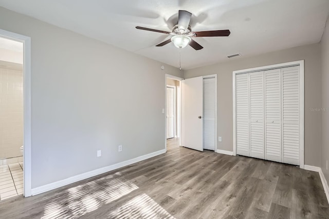 1175 Tracy Dr, Port Orange, FL 32129 - unfurnished bedroom with multiple closets, wood finished floors, ensuite bath, and ceiling fan