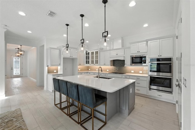 15315 Gilligan Ct, Winter Garden, FL 34787 - kitchen with stainless steel appliances, crown molding, backsplash, white cabinetry, and a kitchen island with sink