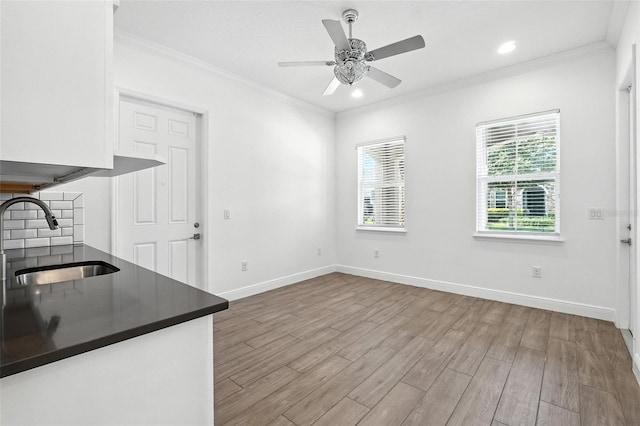 15315 Gilligan Ct, Winter Garden, FL 34787 - kitchen featuring dark countertops, wood finished floors, crown molding, white cabinetry, and ceiling fan