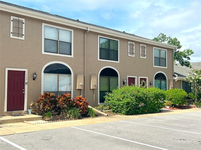 multi unit property with stucco siding and uncovered parking