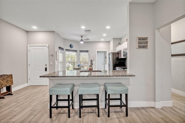 4636 Piedmont St, Orlando, FL 32811 - kitchen featuring a breakfast bar, light wood-style flooring, stainless steel appliances, and recessed lighting