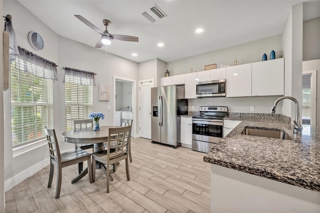 4636 Piedmont St, Orlando, FL 32811 - kitchen with appliances with stainless steel finishes, dark stone counters, white cabinets, independent washer and dryer, and ceiling fan