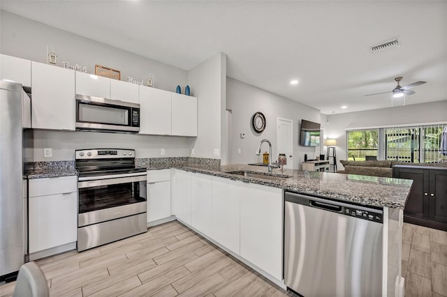 4636 Piedmont St, Orlando, FL 32811 - kitchen featuring stainless steel appliances, a peninsula, white cabinetry, dark stone countertops, and recessed lighting
