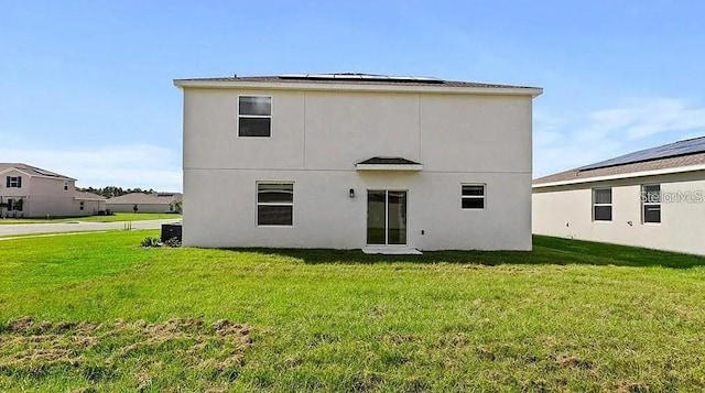 16480 Fernridge St, Clermont, FL 34714 - back of house with a yard, roof mounted solar panels, and stucco siding