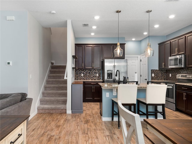2556 Ocoee Reserve Ct, Ocoee, FL 34761 - kitchen featuring appliances with stainless steel finishes, dark brown cabinets, backsplash, a breakfast bar, and recessed lighting