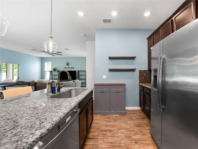 2556 Ocoee Reserve Ct, Ocoee, FL 34761 - kitchen with stainless steel appliances, light wood-style flooring, light stone countertops, open floor plan, and a textured ceiling