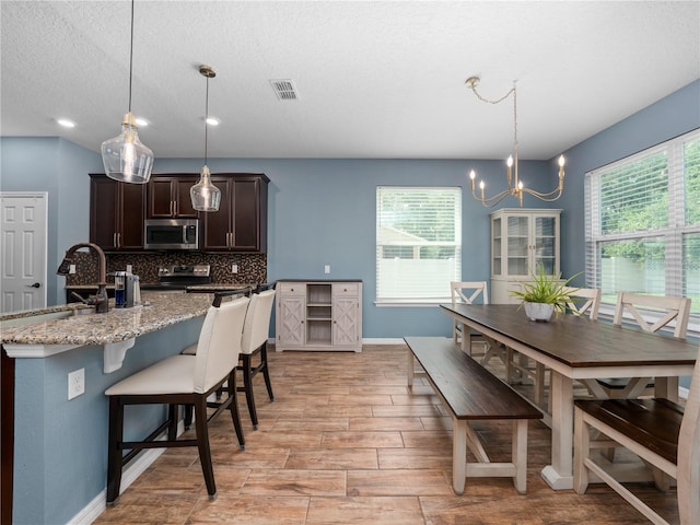 2556 Ocoee Reserve Ct, Ocoee, FL 34761 - kitchen featuring appliances with stainless steel finishes, dark brown cabinets, backsplash, a chandelier, and light wood finished floors