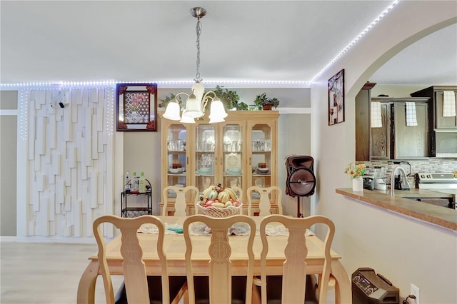 1514 Tamarind Rd, Davenport, FL 33896 - dining room featuring a chandelier, arched walkways, and light wood-style floors